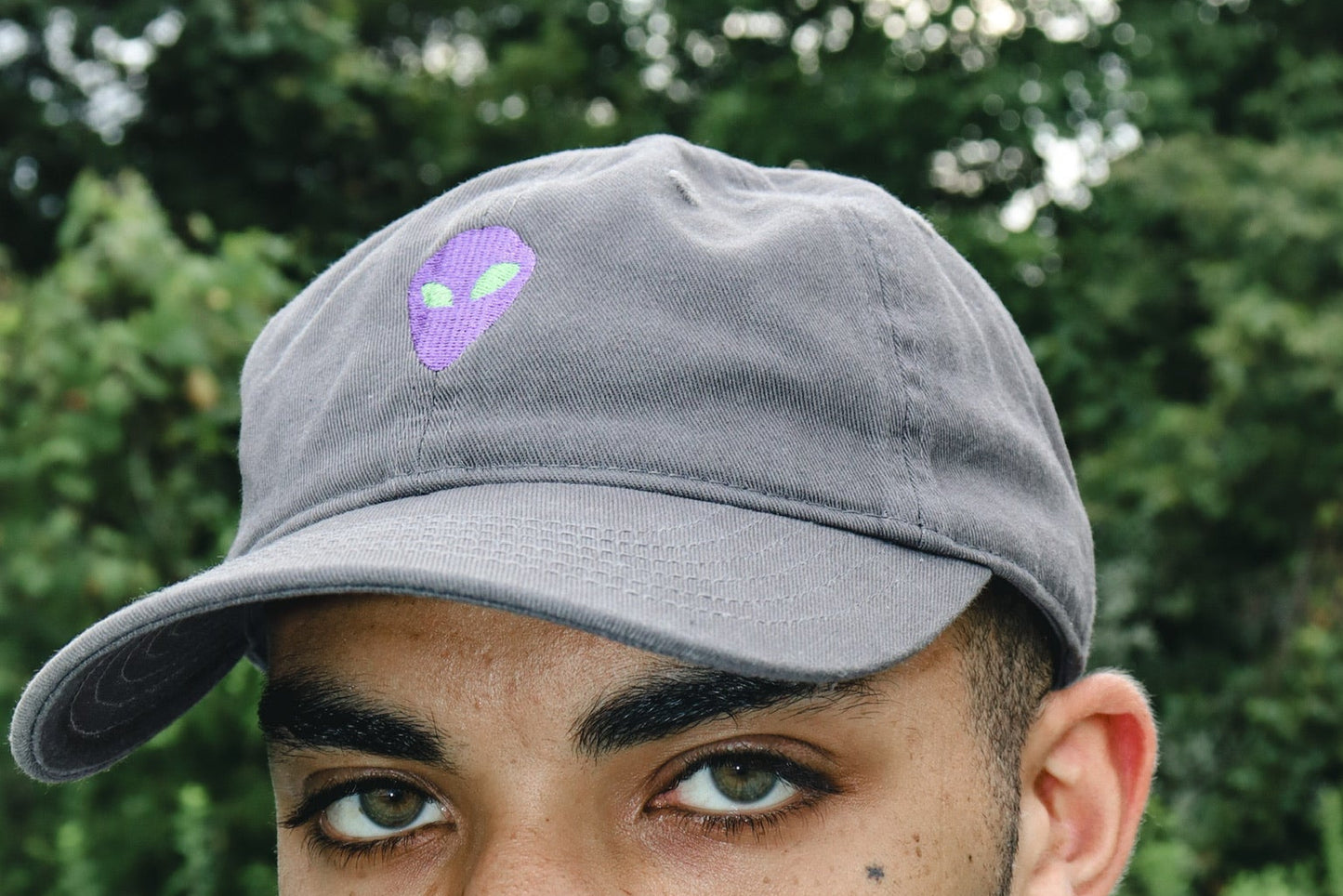 Man wearing a gray cap with an alien outdoors